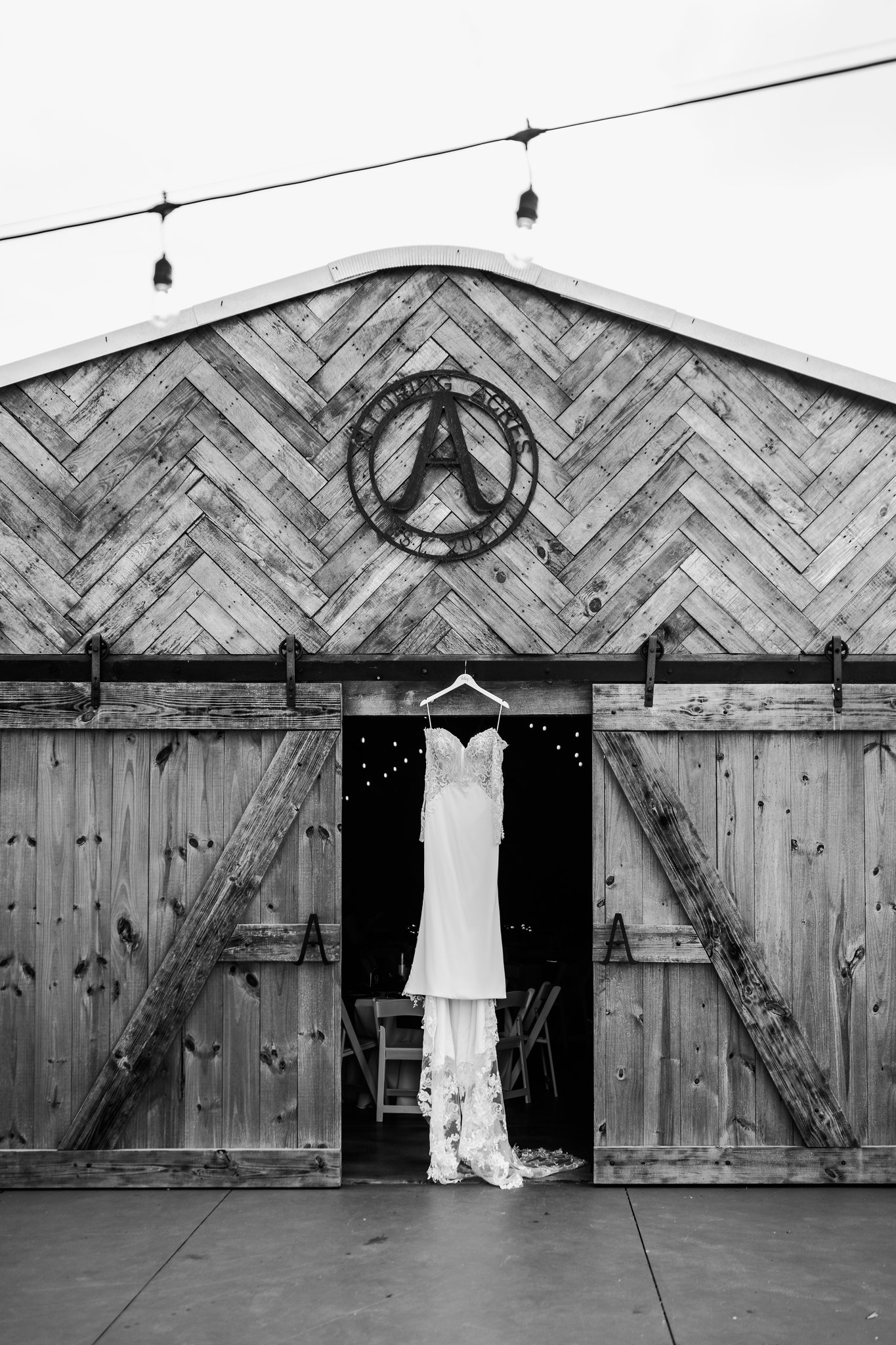 Barn facade with the Alluring Acres sign and a wedding dress in the doorway