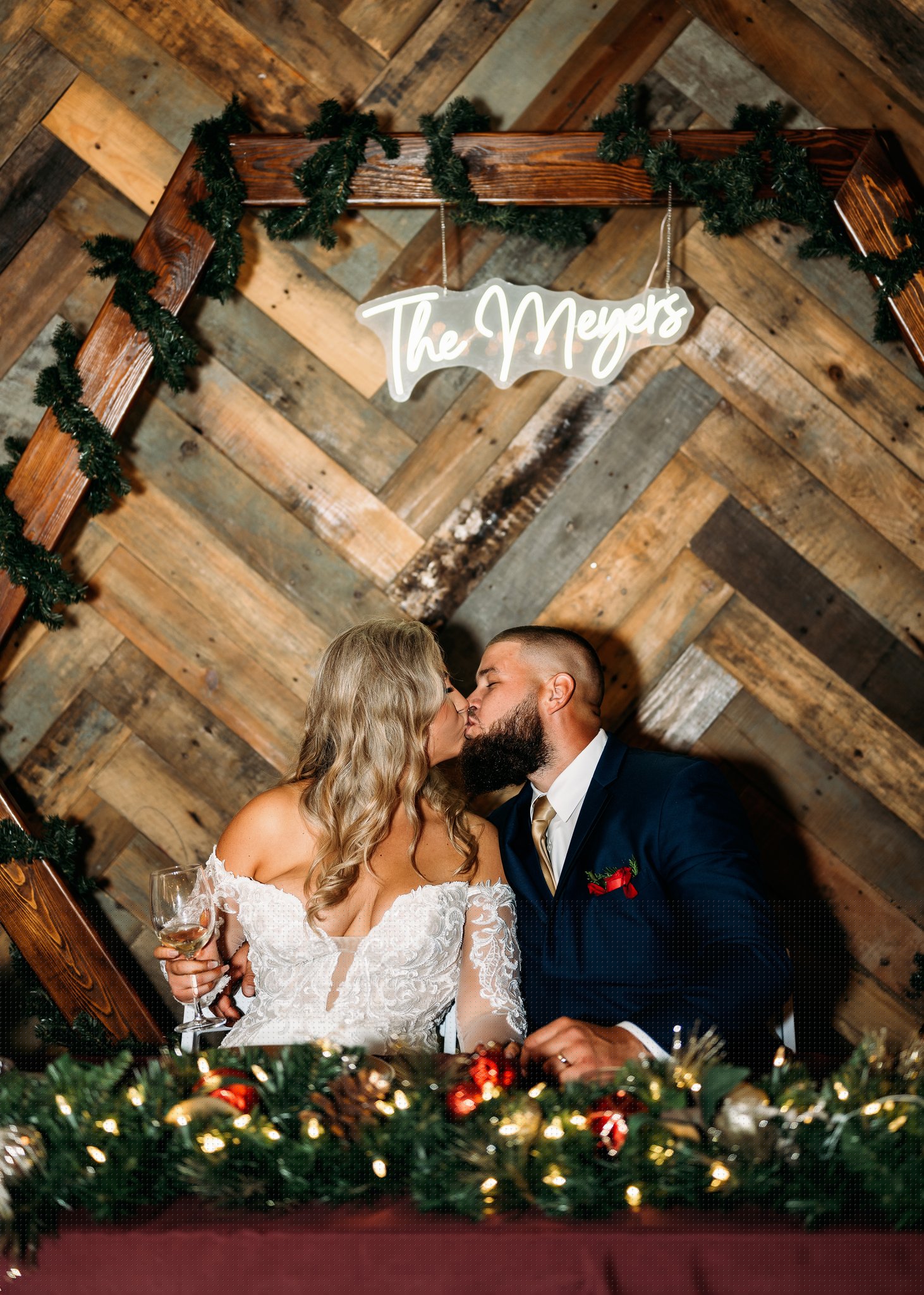 Kiss at the sweetheart table inside the barn