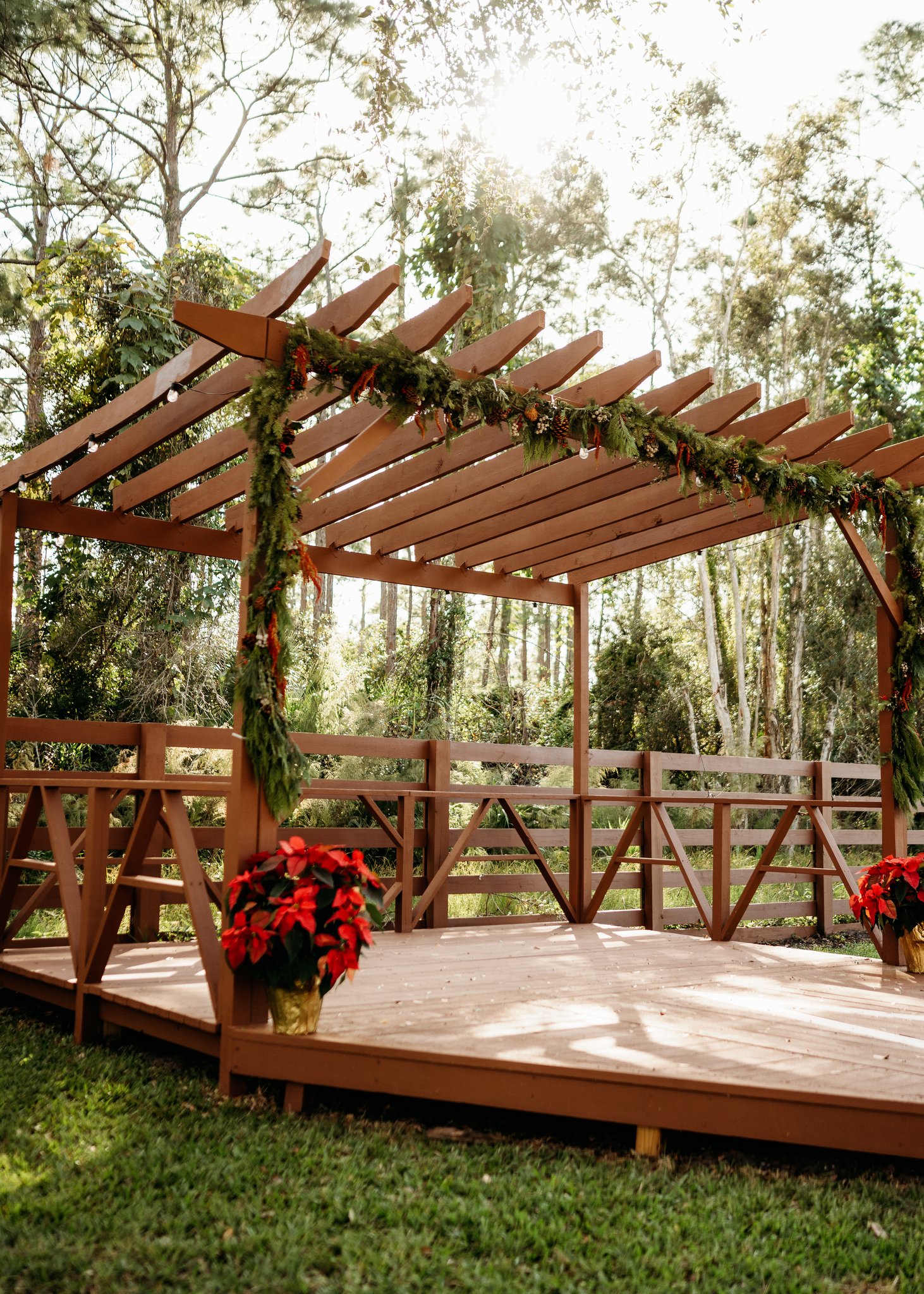 Sunlit ceremony pergola draped in garland at Alluring Acres